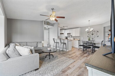 Living area featuring a textured ceiling, a ceiling fan, light wood finished floors, and a chandelier