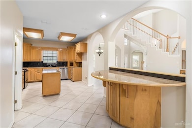 Kitchen featuring dishwasher, a peninsula, light tile patterned flooring, a kitchen island, and a breakfast bar area