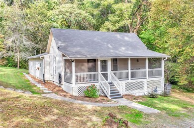 View of front facade featuring a forest view, a front lawn, and a sunroom