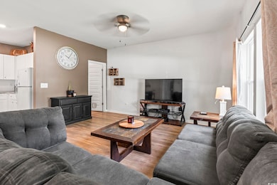 Living room with ceiling fan, light wood-style flooring, and baseboards