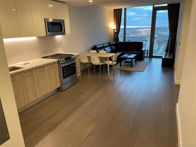 Kitchen featuring modern cabinets, stainless steel appliances, dark wood-type flooring, open floor plan, and light stone counters