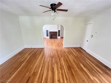 Empty room with ornamental molding, light wood-type flooring, ceiling fan, and a fireplace
