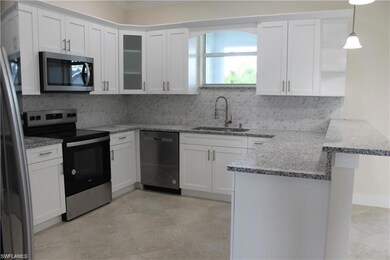 Kitchen with stainless steel appliances, a sink, a peninsula, tasteful backsplash, and white cabinetry