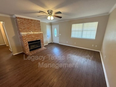 Unfurnished living room with crown molding, a fireplace, dark wood-type flooring, and a ceiling fan