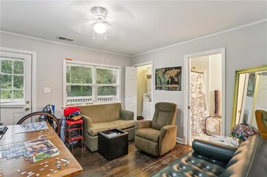 Living room with a ceiling fan, wood finished floors, and ornamental molding