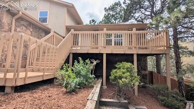 Stairs to Front Entry and deck with many trees and mature shrubs on the lot.