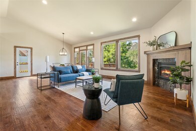Living area featuring vaulted ceiling, dark wood-type flooring, a fireplace, recessed lighting, and a chandelier