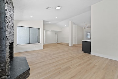 Unfurnished living room featuring lofted ceiling, light wood-style flooring, a chandelier, and a fireplace