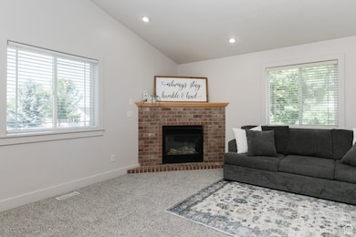 Carpeted living room featuring healthy amount of natural light, lofted ceiling, a fireplace, and recessed lighting
