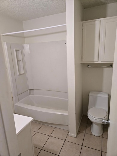 Full bath with a textured ceiling, tile patterned