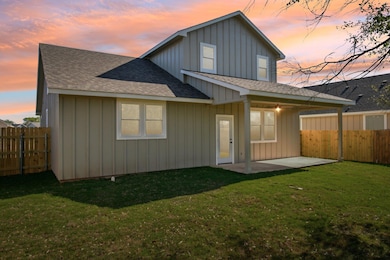 Back of property at dusk featuring fence, roof wi