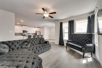Living room with ceiling fan and light wood-type f