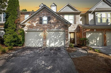 View of front facade with driveway, stone siding, and an attached garage