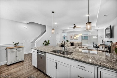 Kitchen with ceiling fan, sink, dark stone counters, stainless steel dishwasher, and pendant lighting
