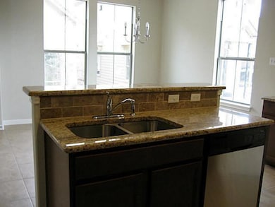 Kitchen with an island with sink, light stone cou