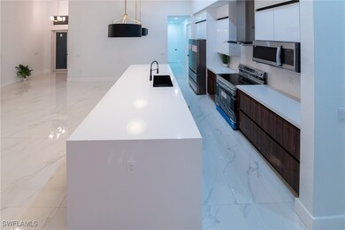 Kitchen with dark brown cabinetry, sink, pendant l