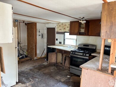 Kitchen with stainless steel range with gas stovetop, freestanding refrigerator, and light countertops