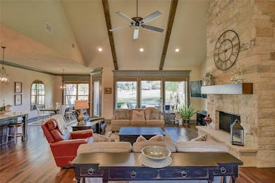 Living room with a healthy amount of sunlight, a stone fireplace, wood-type flooring, and high vaulted ceiling