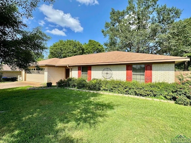 Ranch-style home with brick siding, a front yard, a garage, and concrete driveway