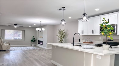 Kitchen featuring pendant lighting, appliances with stainless steel finishes, white cabinets, light stone countertops, and open floor plan