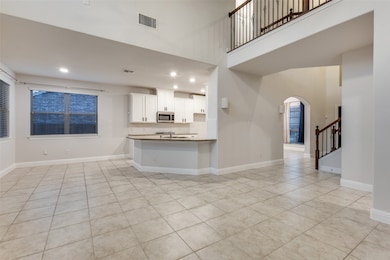 Kitchen with white cabinets, light tile patterned floors, arched walkways, recessed lighting, and backsplash