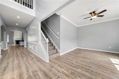 Unfurnished living room featuring a ceiling fan, arched walkways, stairs, wood finished floors, and baseboards