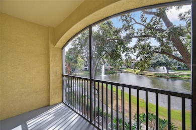 The private screened balcony has serene pond views and is framed by graceful oak trees and a sparkling fountain. This peaceful outdoor space is perfect for enjoying your morning coffee, relaxing with a book, or unwinding at sunset while watching the water shimmer below. The arched architectural detail adds charm, while the screen enclosure ensures year-round comfort and bug-free enjoyment. With tranquil water views and lush landscaping, this balcony offers the ideal Florida retreat right at home.