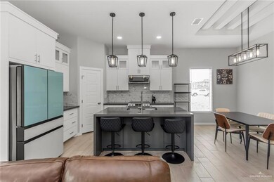 Kitchen with appliances with stainless steel finishes, tasteful backsplash, light hardwood / wood-style floors, and decorative light fixtures