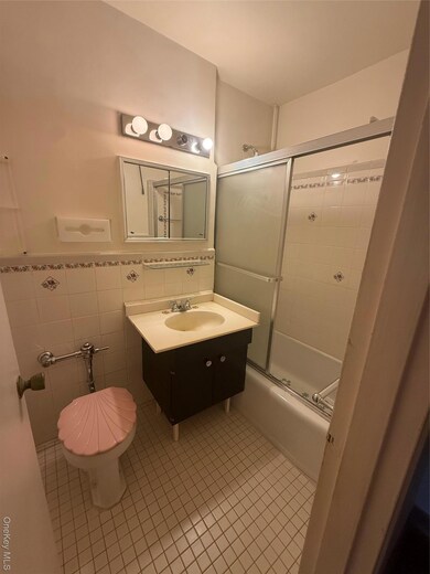Bathroom with tile patterned floors, tile walls, vanity, and shower / bath combination with glass door