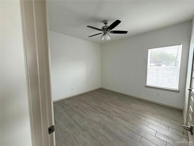 Spare room with wood finished floors, a ceiling fan, and baseboards