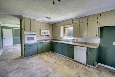 Kitchen featuring a textured ceiling, a sink, gree