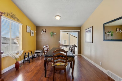 Dining area with a textured ceiling and dark wood-style flooring
