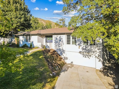 Single story home with brick siding, a mountain view, driveway, an attached garage, and a front lawn