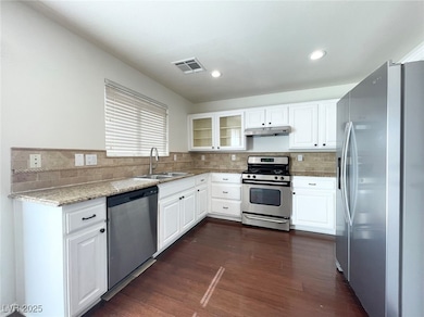 Kitchen with appliances with stainless steel finishes, white cabinets, glass insert cabinets, and recessed lighting