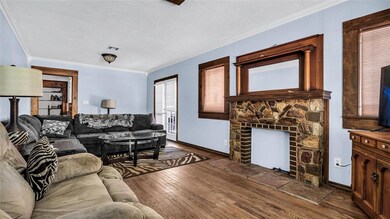 Living room with crown molding, a stone fireplace,