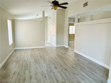 Empty room with vaulted ceiling, ceiling fan, wood