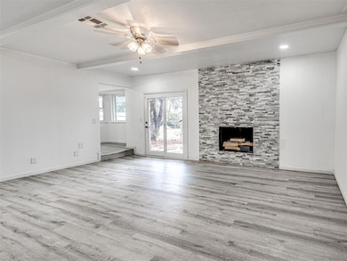 Unfurnished living room with light wood finished floors, a fireplace, a ceiling fan, beamed ceiling, and recessed lighting
