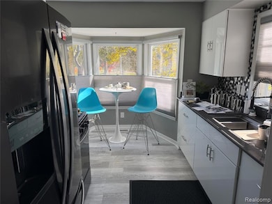 Kitchen featuring dark countertops, black appliances, white cabinets, and light wood-style floors