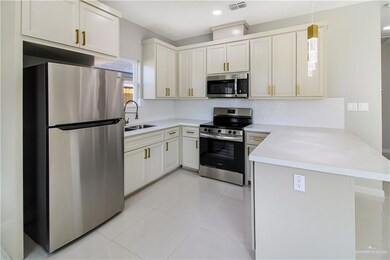 Kitchen with appliances with stainless steel finishes, a sink, a peninsula, decorative backsplash, and light countertops