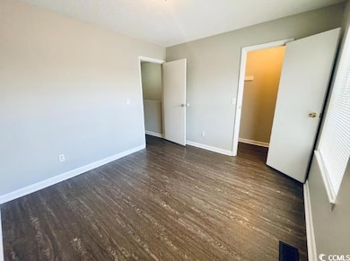 Unfurnished bedroom featuring dark wood-style floo