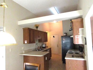 Kitchen featuring a sink, light countertops, a peninsula, white electric range oven, and high vaulted ceiling
