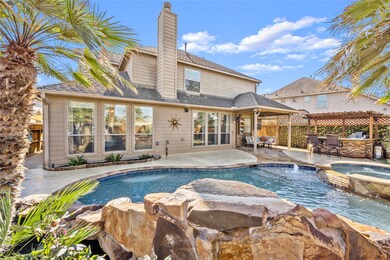 Beautiful pool with rock waterfall, spa, outdoor kitchen and covered patio