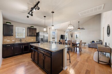 Kitchen with ceiling fan, dark brown cabinets, open floor plan, decorative backsplash, and stainless steel fridge with ice dispenser