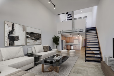 Welcome to 1601 W Webster #9. The expansive first-floor living featuring double-height ceilings and an abundance of natural light. The open layout offers a clear view to the kitchen, while the guest suite, full bath, and utility room are discreetly positioned beyond the stairs. Rear access is located at the end of the hallway. The private primary retreat is located upstairs. This photo is virtually staged.