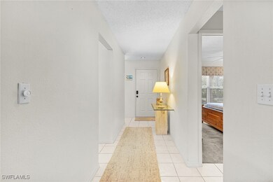Corridor with a textured ceiling, baseboards, and