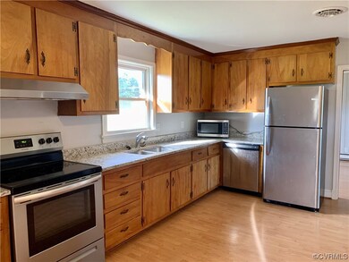 Kitchen with sink, light stone counters, stainless steel appliances, and light hardwood / wood-style flooring