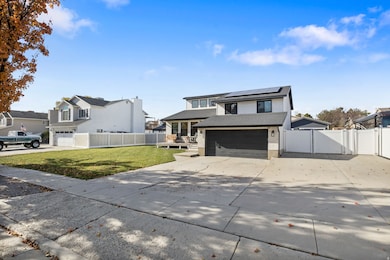 View of front of home with driveway, a gate, an attached garage, solar panels, and roof with shingles