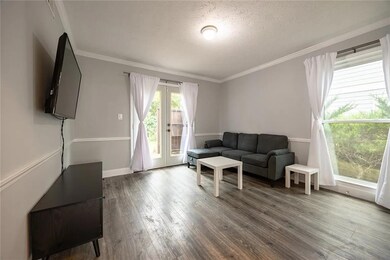 Living room with wood finished floors, ornamental molding, french doors, and a textured ceiling