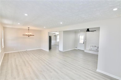 Unfurnished living room featuring baseboards, a te