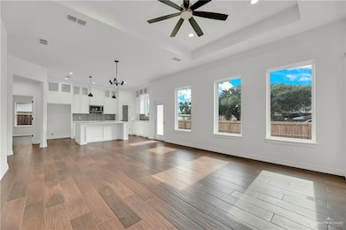 Unfurnished living room featuring a healthy amount of sunlight, ceiling fan with notable chandelier, visible vents, and recessed lighting